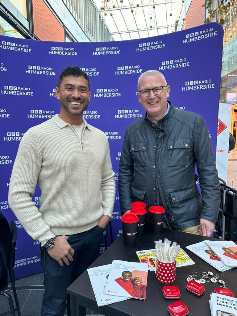 Rav Wilding and Dave Callington of HSBC stand in front of a BBC Humberside purple board while smiling.