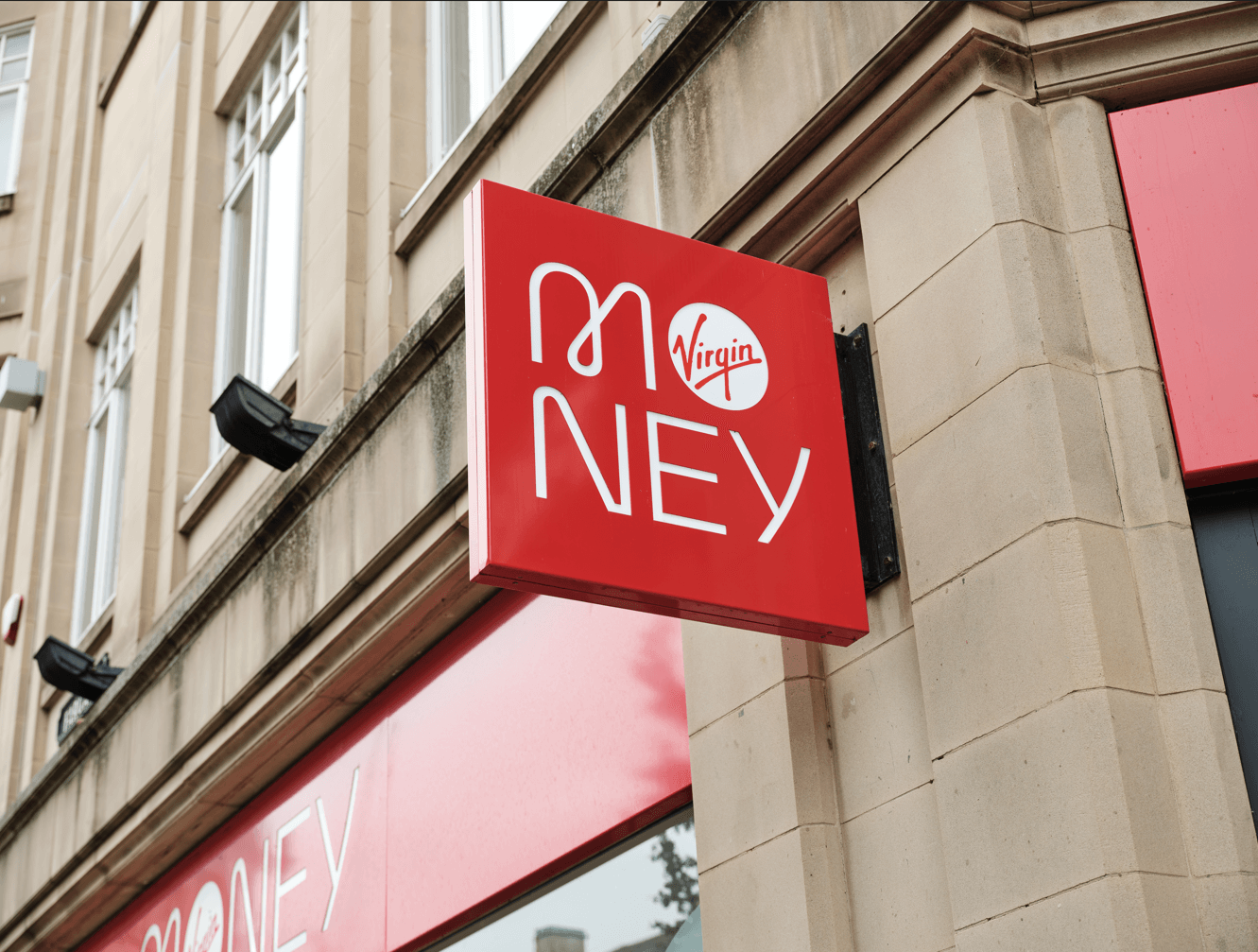 A red sign with the word 'money' written on it as well as the Virgin Money circular logo written in red with a white background.